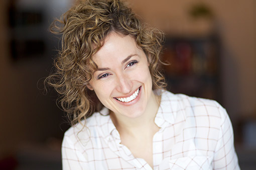 Femme souriante dans un café Calvitie chez la femme | Greffe de cheveux DHI Paris